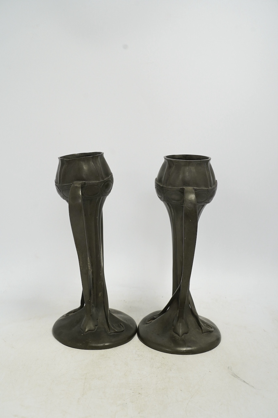 A pair of Art Nouveau Liberty Tudric pewter twin-handled vases, stamped to the bases, 25cm high. Condition - one good, the other poor to fair